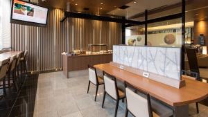 a restaurant with a long wooden table and chairs at Dormy Inn Kumamoto Natural Hot Spring in Kumamoto