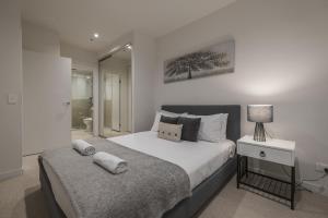 a bedroom with a bed and a night stand with a lamp at Brand New 2br2ba Caulfield Parkbalcony Poolgym in Melbourne +16 photos