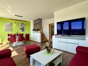 a living room with a large television and red chairs at Ferienwohnung direkt an der Elbe in Coswig