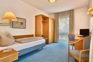 a hotel room with a bed and a desk and a tv at Landhotel Seerose in Langenzenn