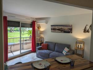 a living room with a couch and a table at Studio dans résidence in Mandelieu-La Napoule
