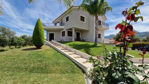 a white house with a palm tree in the yard at Dimitris Villa in Aígio