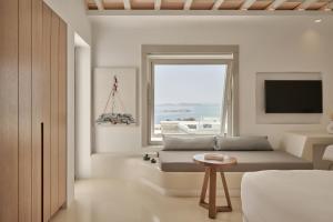 a bedroom with a bed and a window and a television at Ovea Mykonos in Mikonos