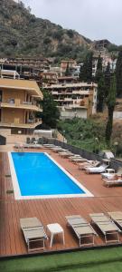 a swimming pool with lounge chairs and a building at COCO SUNSHINE Apartment TAORMINA in Taormina