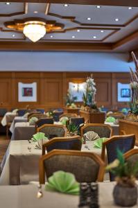 a dining room with tables and chairs with plants at Landhotel Seerose in Langenzenn