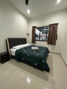 a bedroom with a bed with a green comforter and a window at Green Space Homestay Cozy Family(8-12pax) in Ipoh
