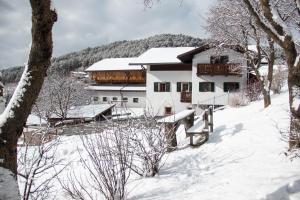 a house in the snow with snow covered trees at Kreuzerhof in Siusi