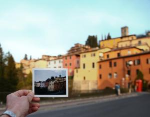 a person holding up a picture of a city at Art Boutique Hotel Acchiappasogni in Barga