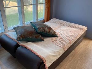 a bed with pillows on it in a room with windows at Green Tree Cottage 4 in Klong Muang Beach