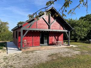 a red barn with chairs and tables in a field at Le chalet in Saint-Lubin-en-Vergonnois