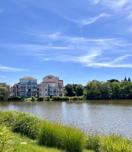 a view of a lake with buildings in the background at l'orée du lac in Talmont +42 photos