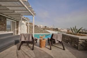 two chairs and a table on a patio with a pool at Ovea Mykonos in Mikonos