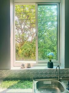 a kitchen window with a sink and a vase of flowers at Morning cozy, airport 5-30 min in Pak Kret