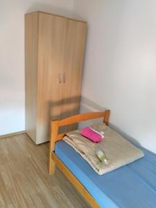 Una cama pequeña en una habitación con un armario de madera. en Altea 1, en Vršac