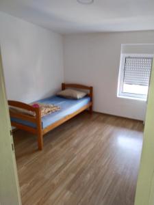 Una pequeña habitación con una cama y una ventana. en Altea 1, en Vršac