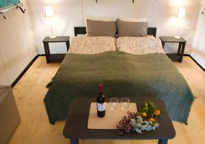 a bed with a bottle of wine and a table with wine glasses at Glempings Eglenieki in Almale +7 photos