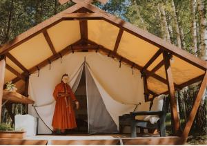 a man standing in front of a tent at Glempings Eglenieki in Almale