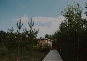 una pasarela de madera que conduce a una cabaña en el bosque en Glempings Dīķīši, en Stākas
