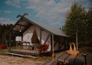 Una carpa blanca y negra con una mesa y flores. en Glempings Dīķīši, en Stākas