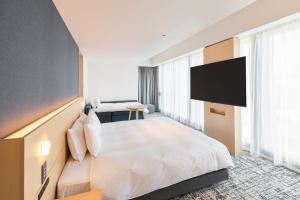 a hotel room with a bed and a flat screen tv at Sotetsu Hotels The Splaisir Yokohama in Yokohama