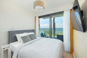 sypialnia z łóżkiem i dużym oknem w obiekcie HS Apartamenty Hevenia Sun widok na morze w Rewalu