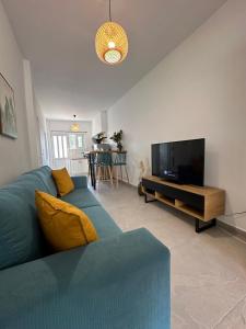 a living room with a blue couch and a flat screen tv at Seaside Modern House Katakolo in Katakolo