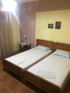 two twin beds in a bedroom with a light on at Thomas Vrasna Close To The Sea in Nea Vrasna