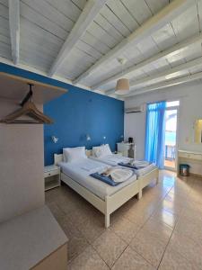 a bedroom with a large bed with a blue wall at Faros Rooms in Loutro