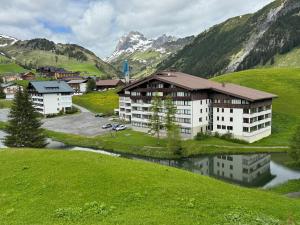 an apartment building in a valley with a river and mountains at TOP 40 Haus Sonnalp in Warth am Arlberg