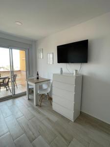 a living room with a tv on the wall and a table at Estudio Oceanview Torre del Mar in Torre del Mar