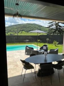 a patio with a table and chairs and a pool at Villa avec piscine chauffée in Ancy