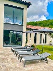 a row of benches with umbrellas in front of a building at Villa avec piscine chauffée in Ancy