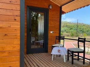 un portico di una casa di legno con un tavolo e due sedie di Hane-i Keyif Pension a Çıralı