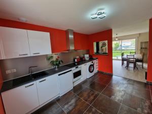 a kitchen with white cabinets and red walls at Gite Le Garage in Magny-Cours