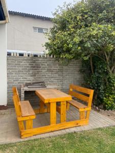 a wooden picnic table and two chairs next to a brick wall at KleinHenties in Hentiesbaai +1 photo