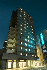 ein hohes Gebäude mit einem Schild darauf in der Nacht in der Unterkunft Sotetsu Fresa Inn Kitahama in Osaka