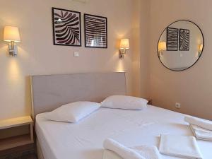 a white bed with two pillows and a mirror at Faros Apartments in Mytikas