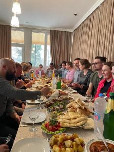 a group of people sitting at a long table with food at Hostel Kutaisi by Kote in Kutaisi