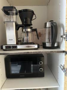a black microwave sitting on a shelf in a kitchen at Rubin Apartment - moderni huoneisto lähellä keskustaa in Kajaani