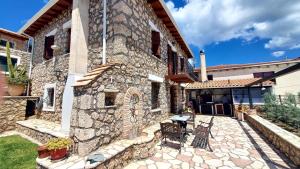 a stone building with a table and chairs in front of it at Three Hearts in Áyios Pétros
