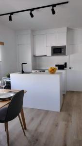 a kitchen with white cabinets and a table with a bowl of fruit at Valdoviño Experience in Valdoviño