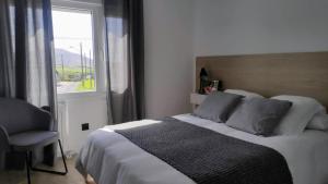 a bedroom with a bed with a window and a chair at Valdoviño Experience in Valdoviño
