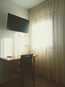 einen Schreibtisch mit einem Monitor, einem Stuhl und einem Fenster in der Unterkunft H&G LOZOYUELA in Lozoyuela