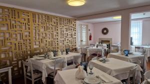 a dining room with white tables and chairs and a wall at Hotel Central Jardim in Geres