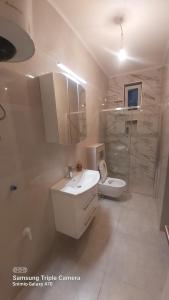 a white bathroom with a sink and a toilet at AMY APARTMAN in Tuzla