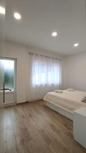 a white bedroom with a bed and a window at Bungevilia Apartment in Gruda