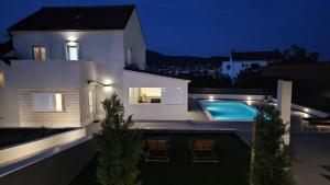 a white house with a swimming pool at night at Villa Stone - Pool house 100 meters from the beach in Vinišće