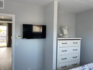 una camera da letto con cassettiera e TV a parete di Settle In the Sun at The Carideon Family Resort a North Wildwood Altre 2 foto