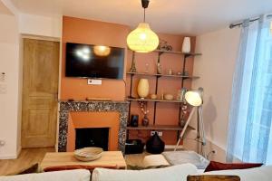 ein Wohnzimmer mit einem Kamin und einem Flachbild-TV in der Unterkunft Coup de Cœur D'Auxerre in Auxerre