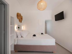 a bedroom with a white bed with two flowers on it at M&M Parikia's Old Town Studio in Parikia